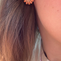 Arete floral coral colocado en oreja