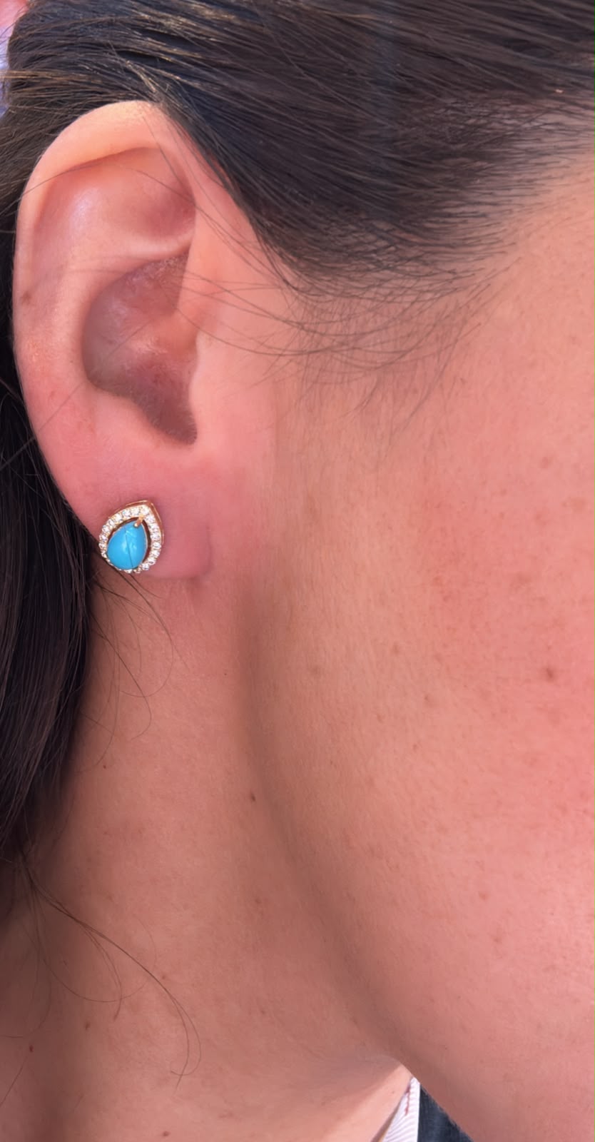 Arete azul en forma de gota con halo de piedras brillantes lucido en oreja