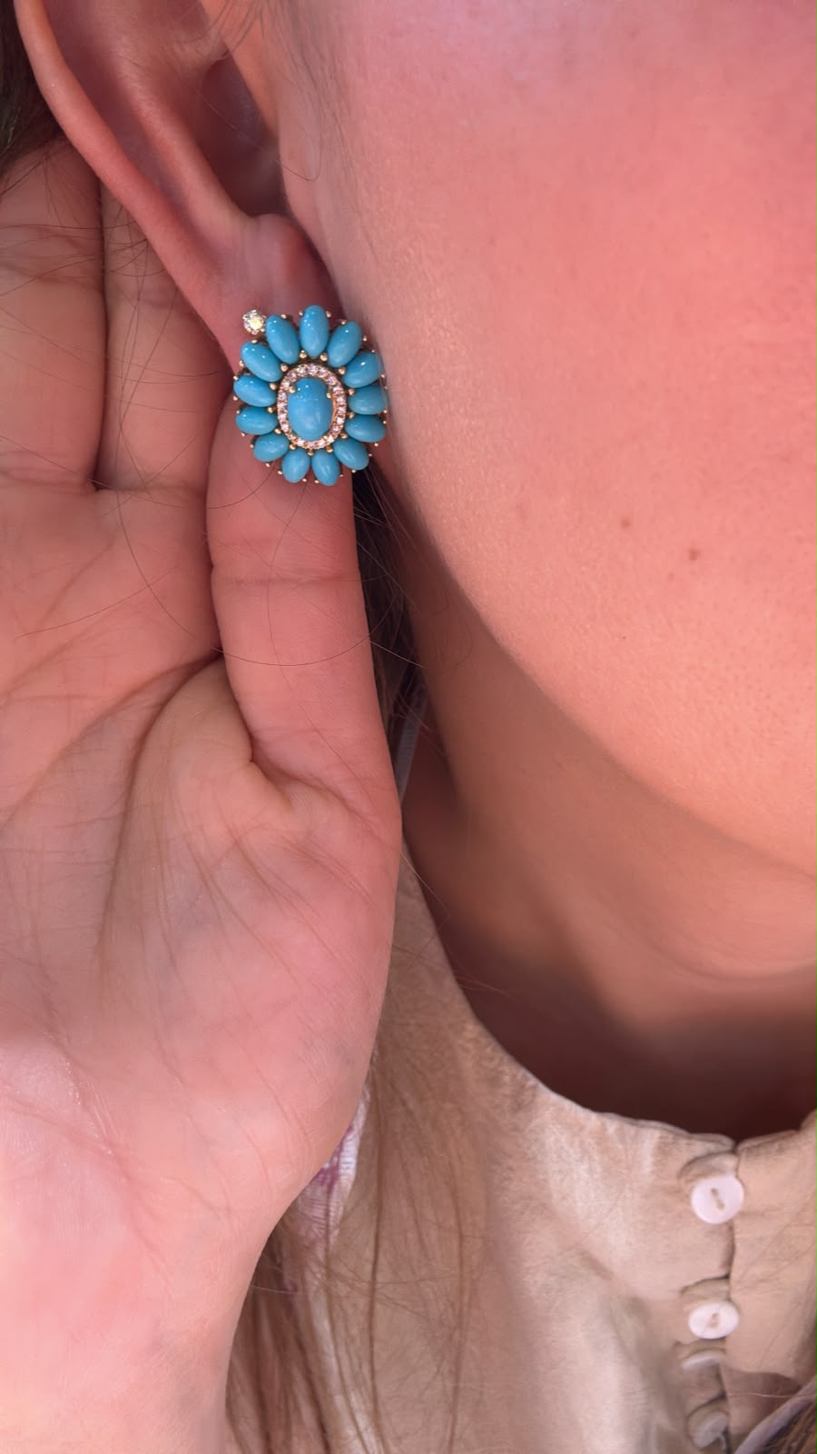 Arete turquesa de forma floral colocado en oreja