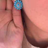 Arete turquesa de forma floral colocado en oreja